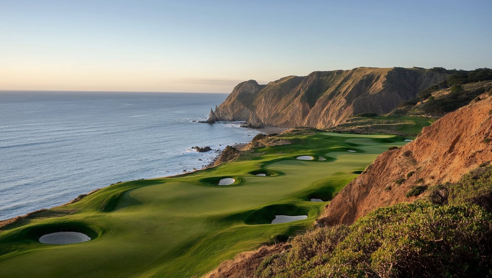 A cliffside green above the sea, framed by dramatic coastal terrain